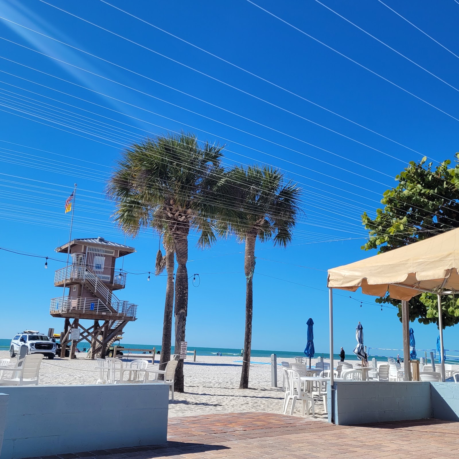 Palm trees and a beach umbrella framing the lifeguard tower and Gulf at Manatee Beach