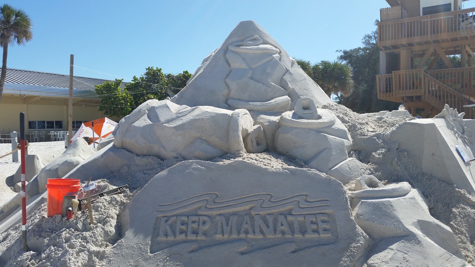 Large carved sand sculpture reading Keep Manatee on the beach near the cafe